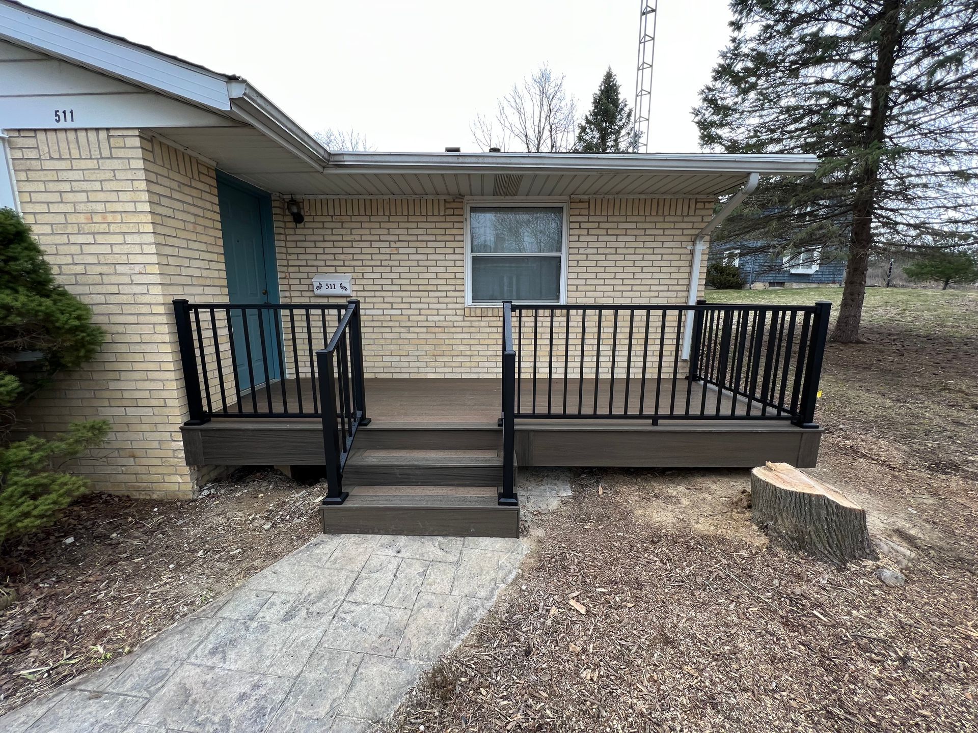 A small brick house with a porch and stairs.