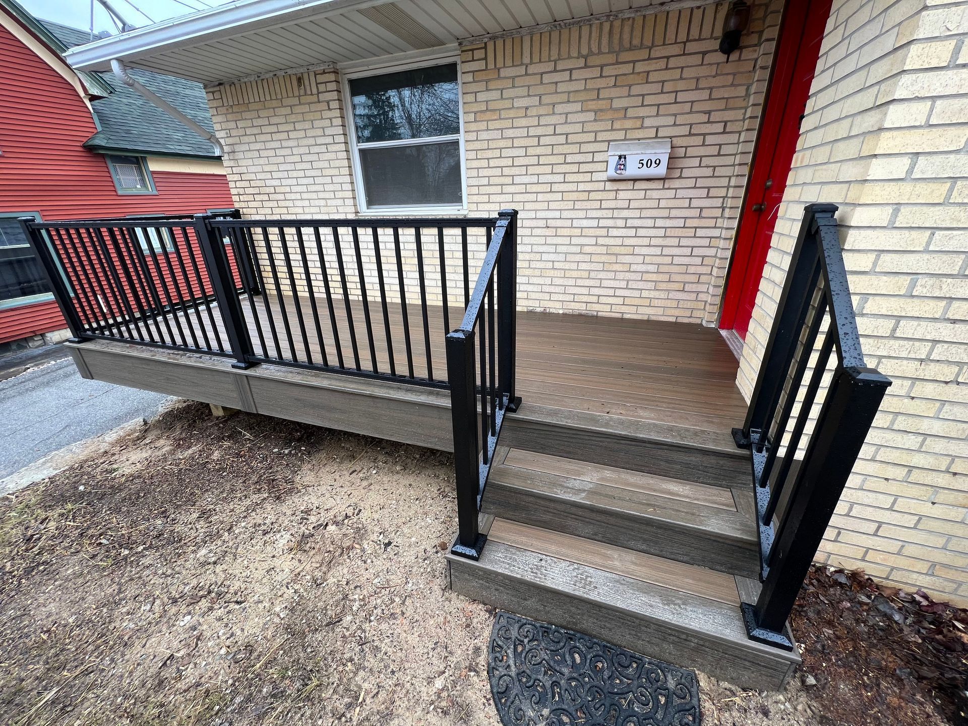 A brick house with a black railing and stairs leading up to it.