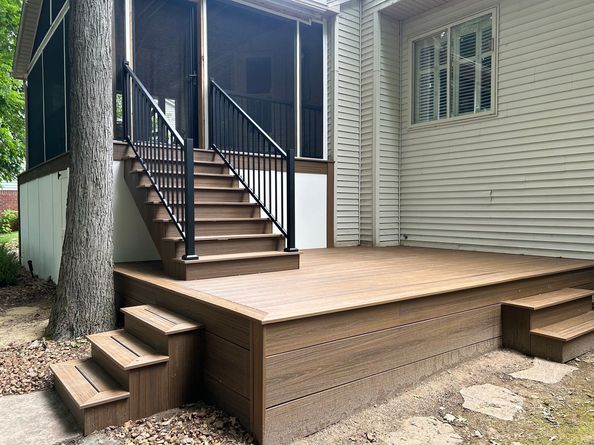 A wooden deck with stairs leading up to a screened in porch
