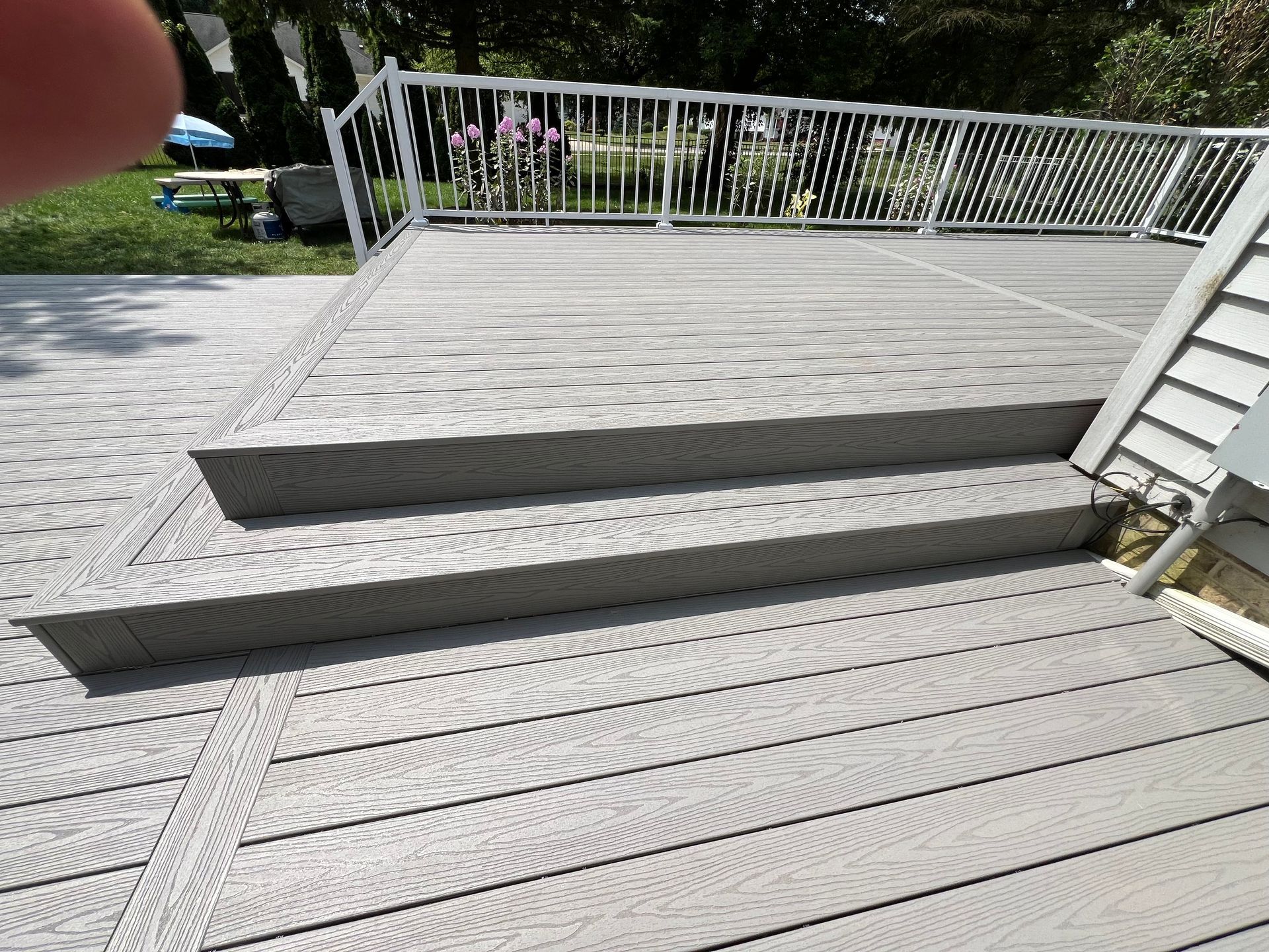 A wooden deck with stairs leading up to it and a metal railing.