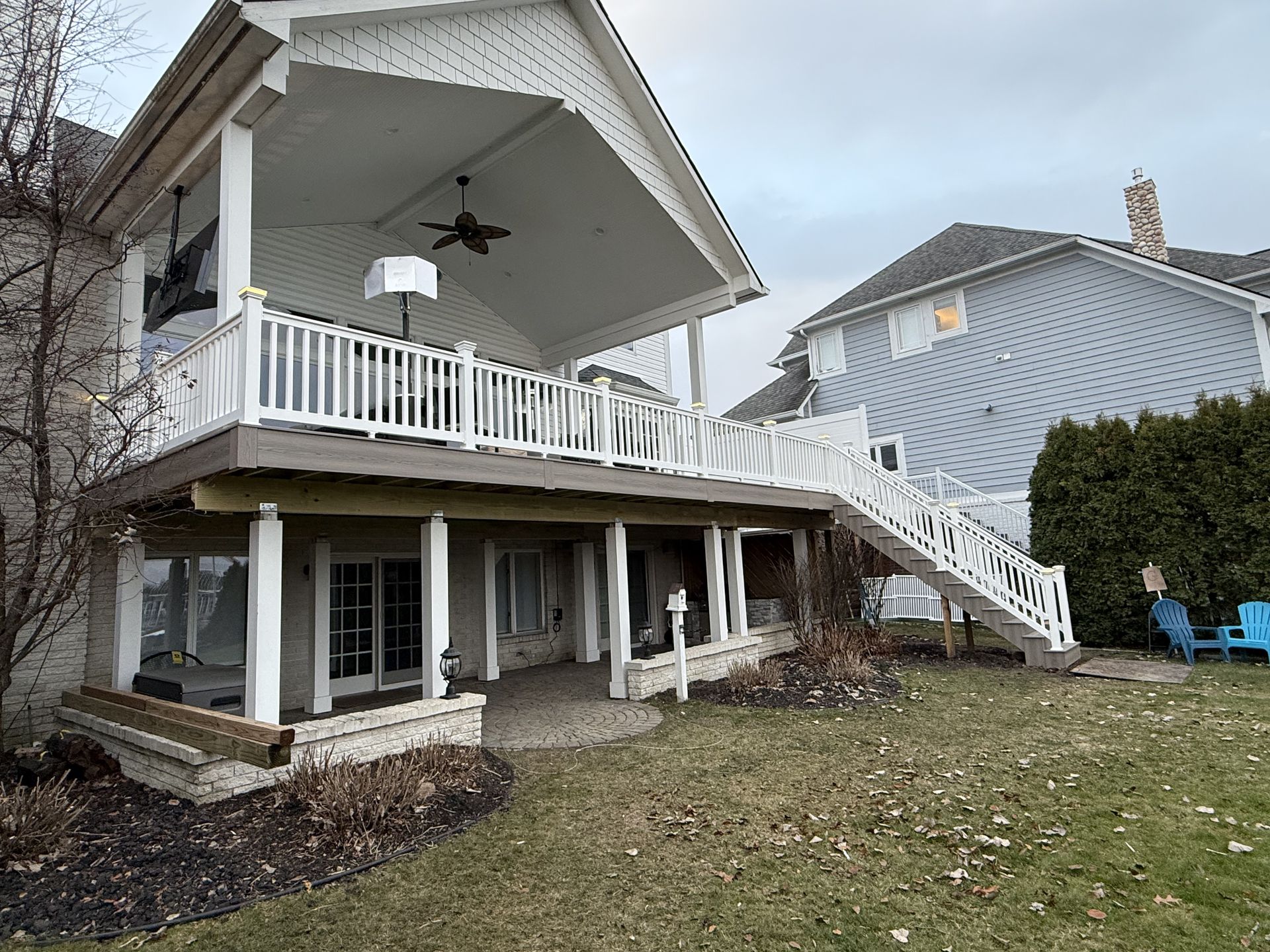 The back of a house with a large deck and stairs leading up to it.