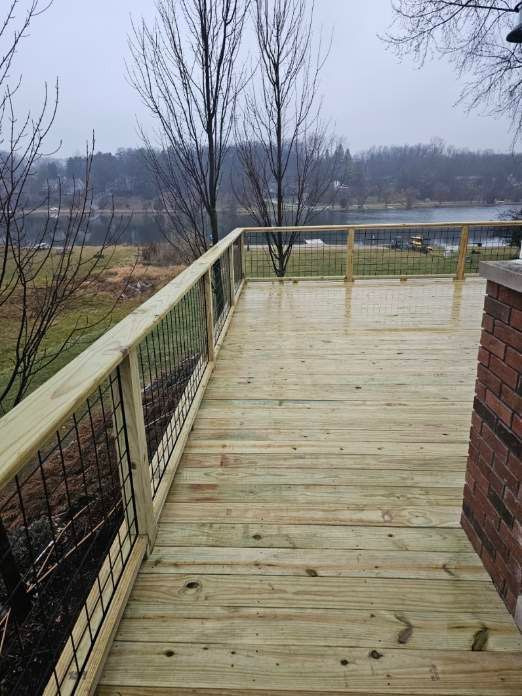 A wooden deck with a view of a lake and trees