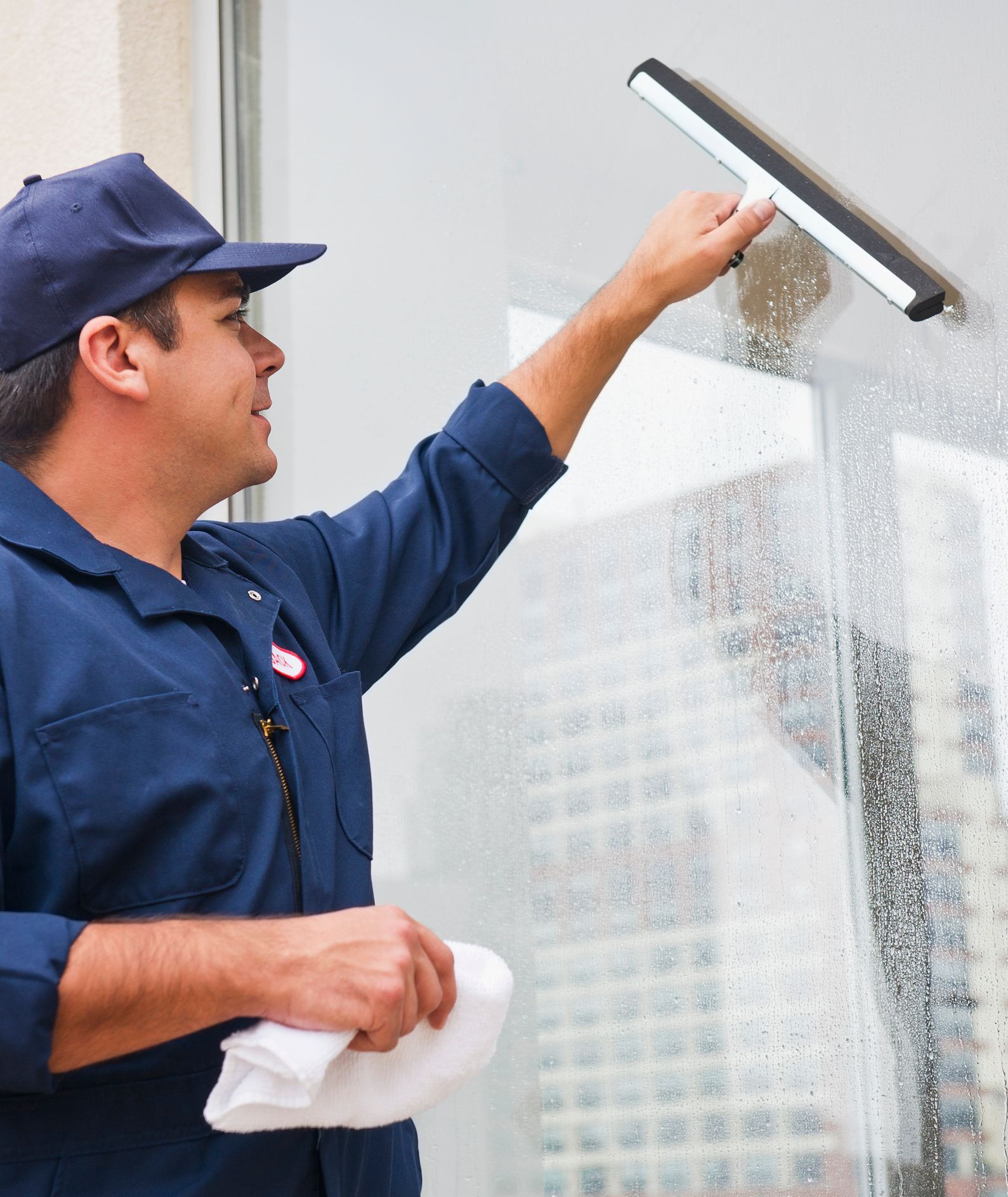 A man carefully cleaning a window for a clear, spotless finish A man carefully cleaning a window for a clear, spotless finish