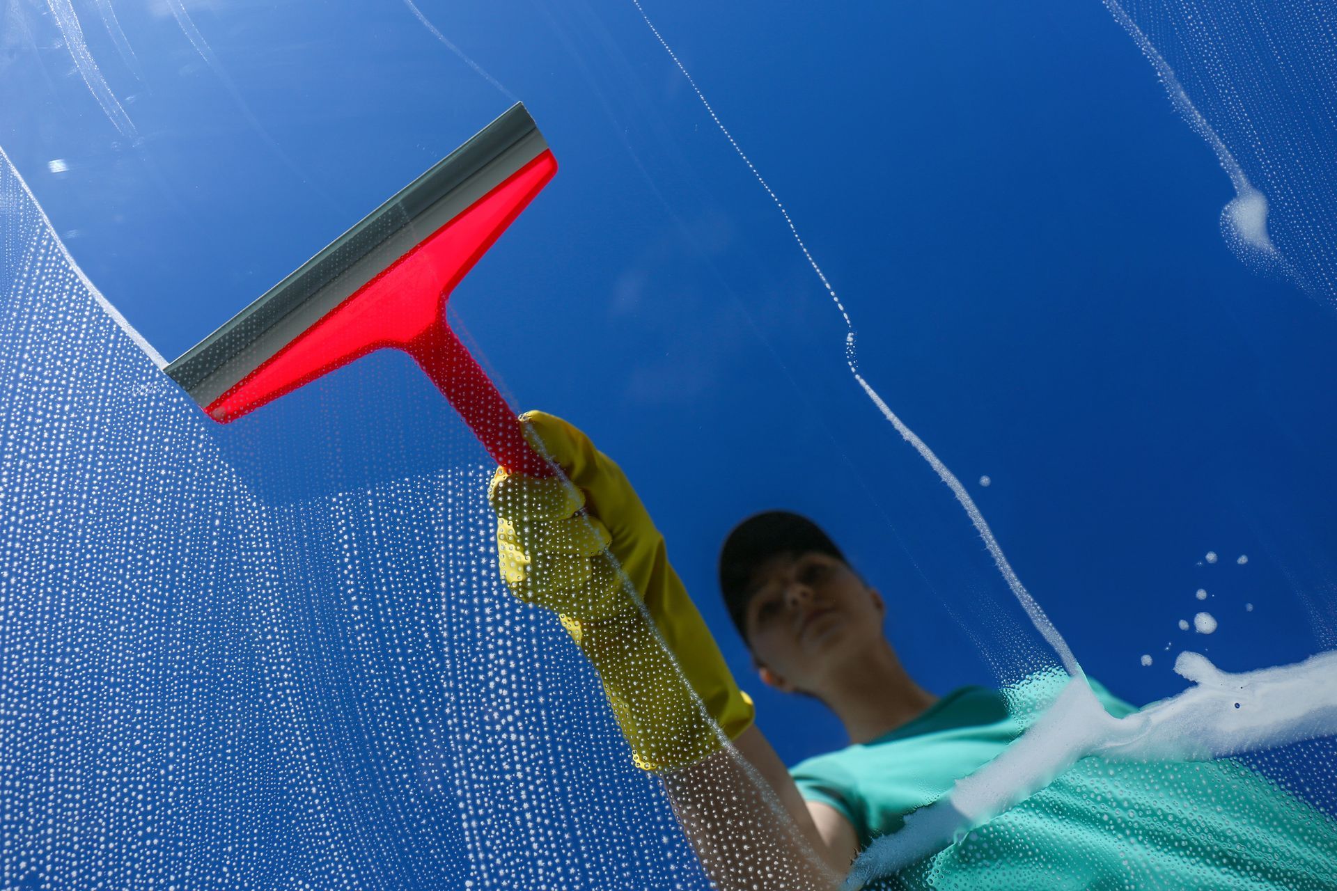 Woman cleaning glass with a squeegee on a bright sunny day.