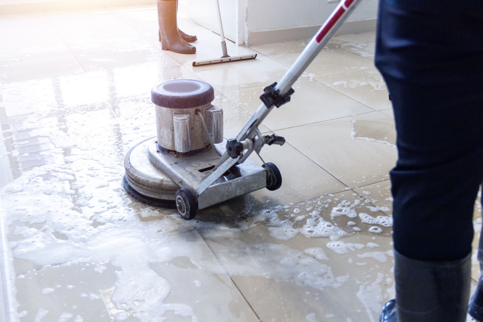 Two janitors use a floor scrubber machine on the floor of a hallway, office building, or walkway. Two janitors use a floor scrubber machine on the floor of a hallway, office building, or walkway.
