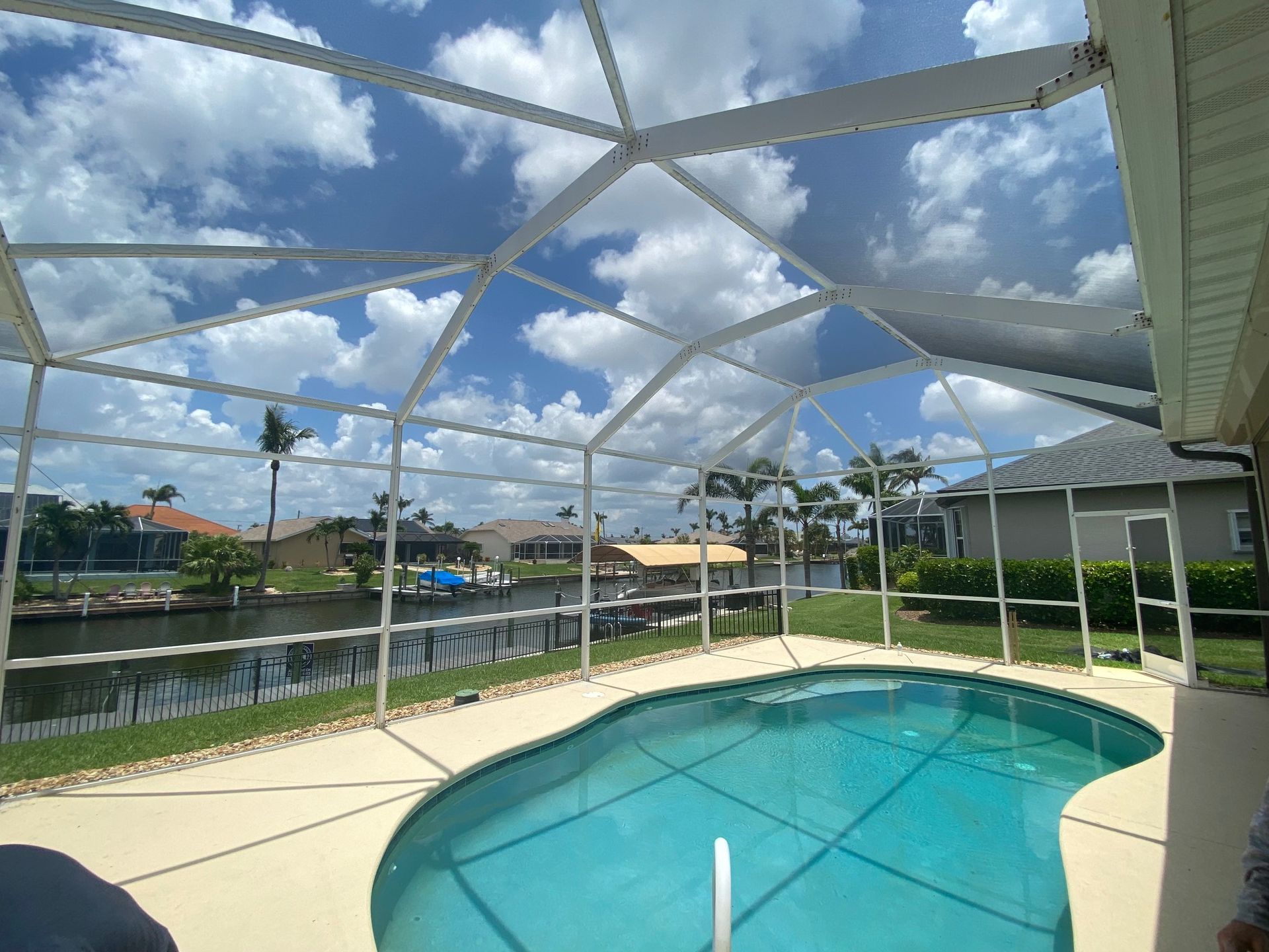 A large swimming pool is surrounded by a screened in area.