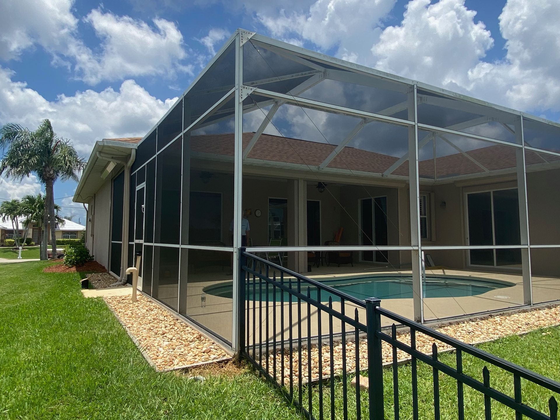 A house with a screened in pool and a fence around it.