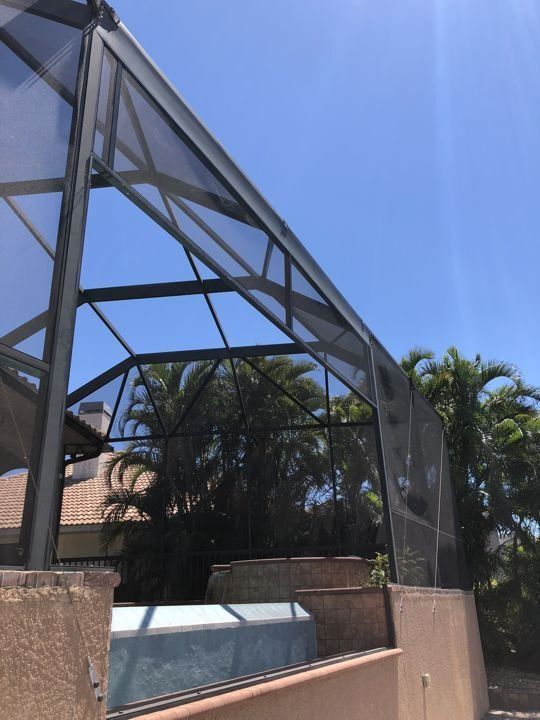 A screened in area with palm trees in the background