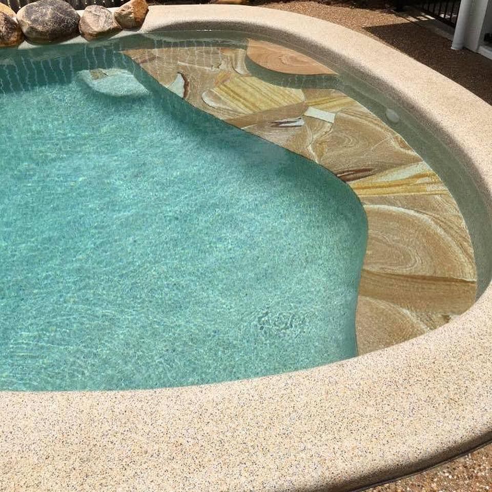 Pool with light blue water and stone steps. Beige concrete border— Tru Blu Pools & Spas in Bluewater, QLD