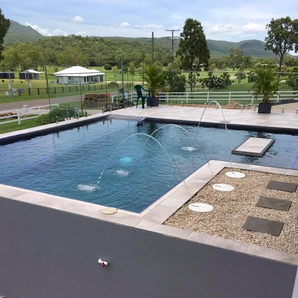 Pool with fountains, patio, and landscaped yard. Green mountains in the background— Tru Blu Pools & Spas in Bluewater, QLD
