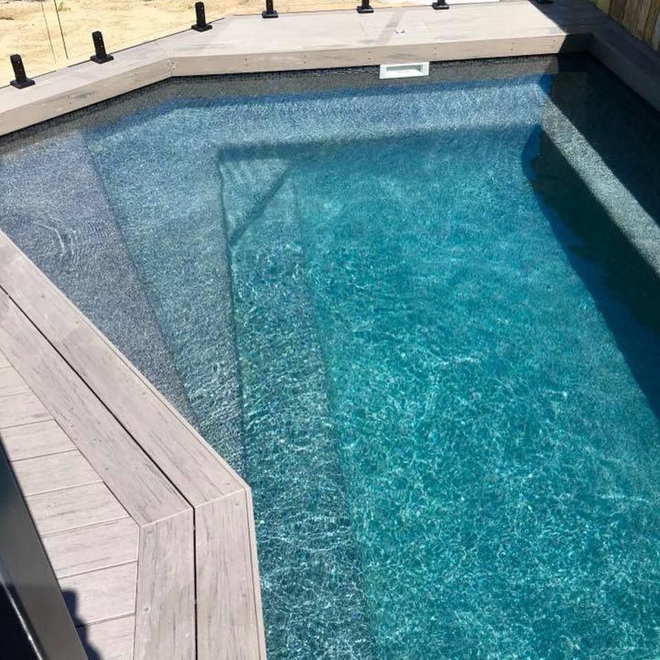 Swimming pool with steps, turquoise water, surrounded by concrete and wooden decking— Tru Blu Pools & Spas in Bluewater, QLD