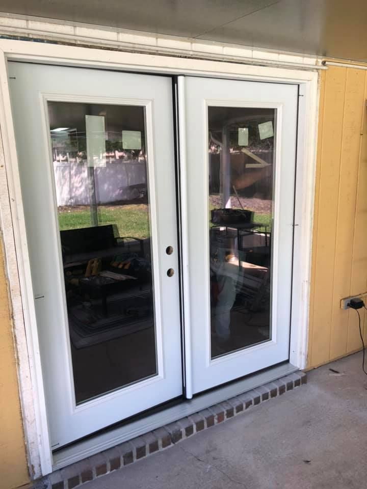 A pair of white french doors are open to a patio.