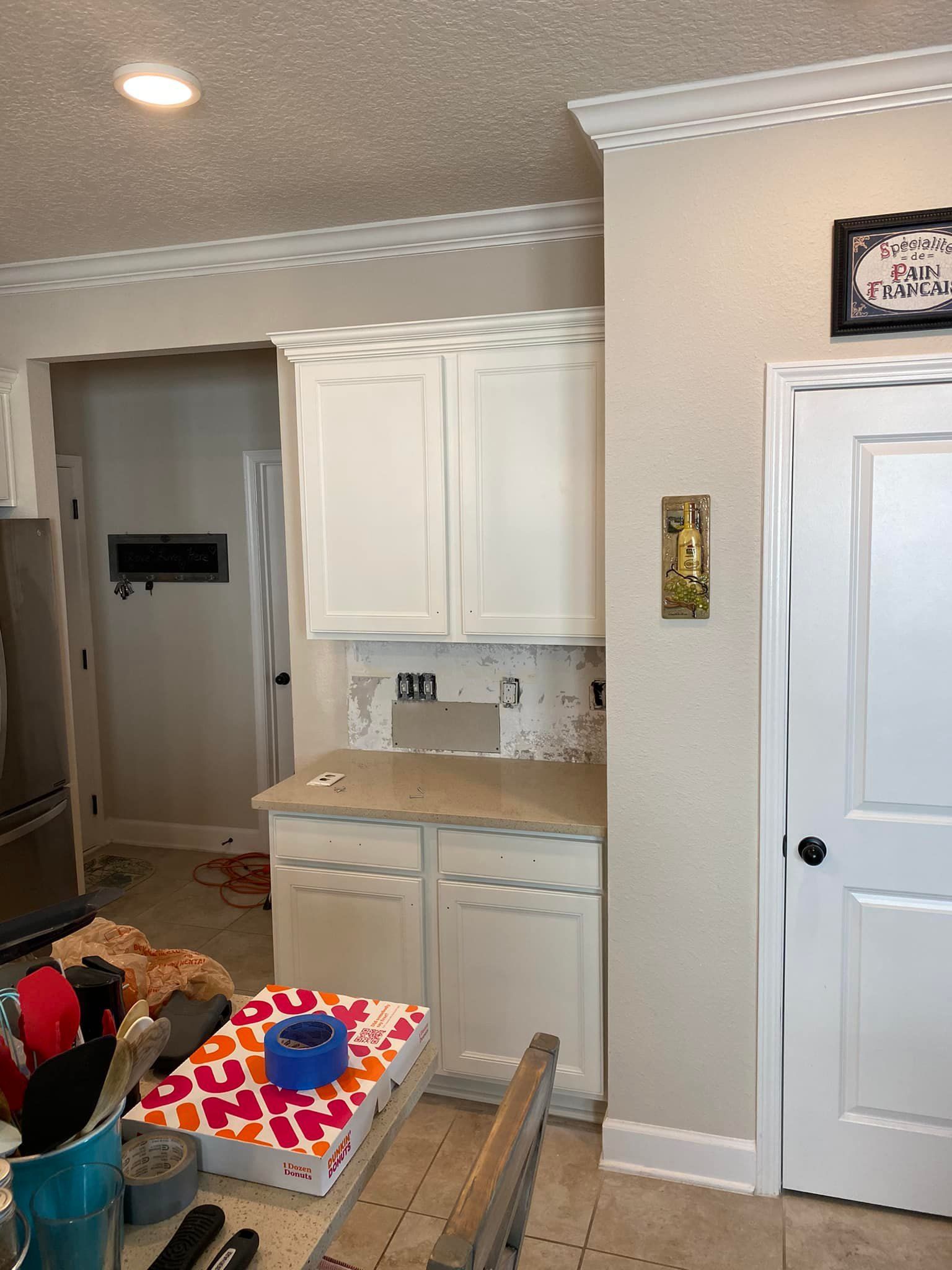 A kitchen with white cabinets and a ladder on the floor.