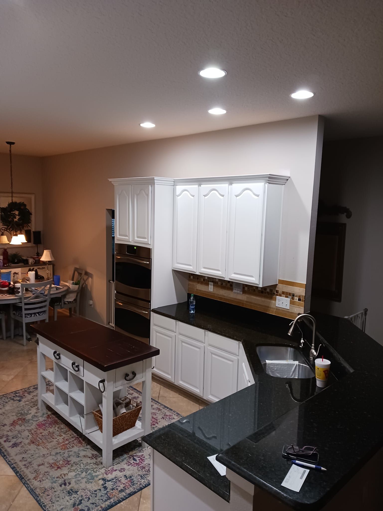 A kitchen with white cabinets and a black counter top