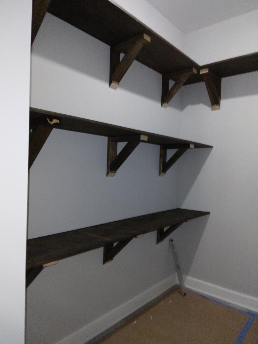 A corner of a room with shelves and a ladder