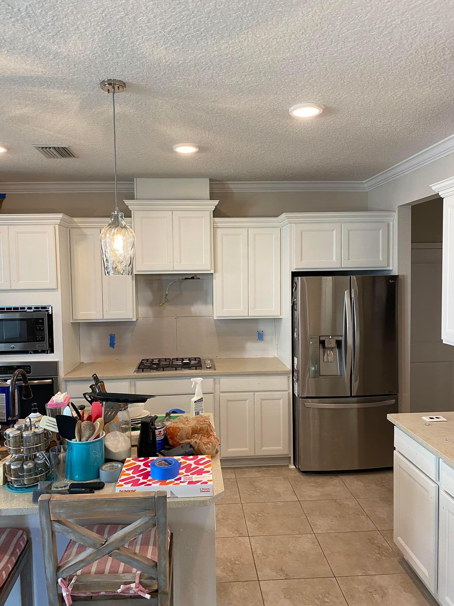 A kitchen with white cabinets and a stainless steel refrigerator.