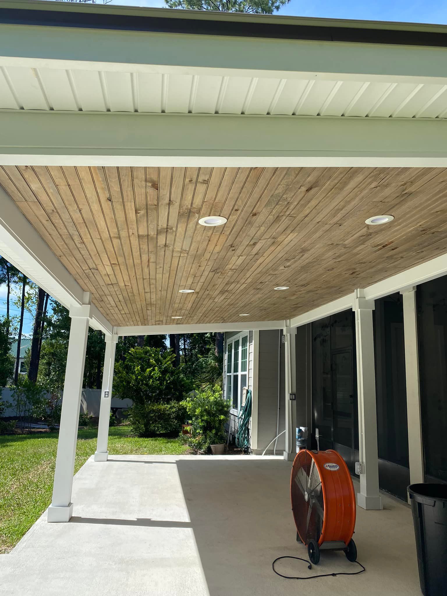 A porch with a wooden ceiling and a fan on it.