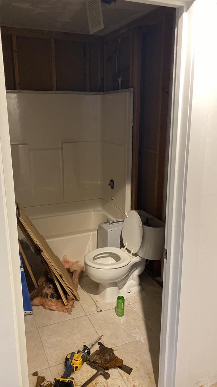 A bathroom with a toilet , tub and shower under construction.