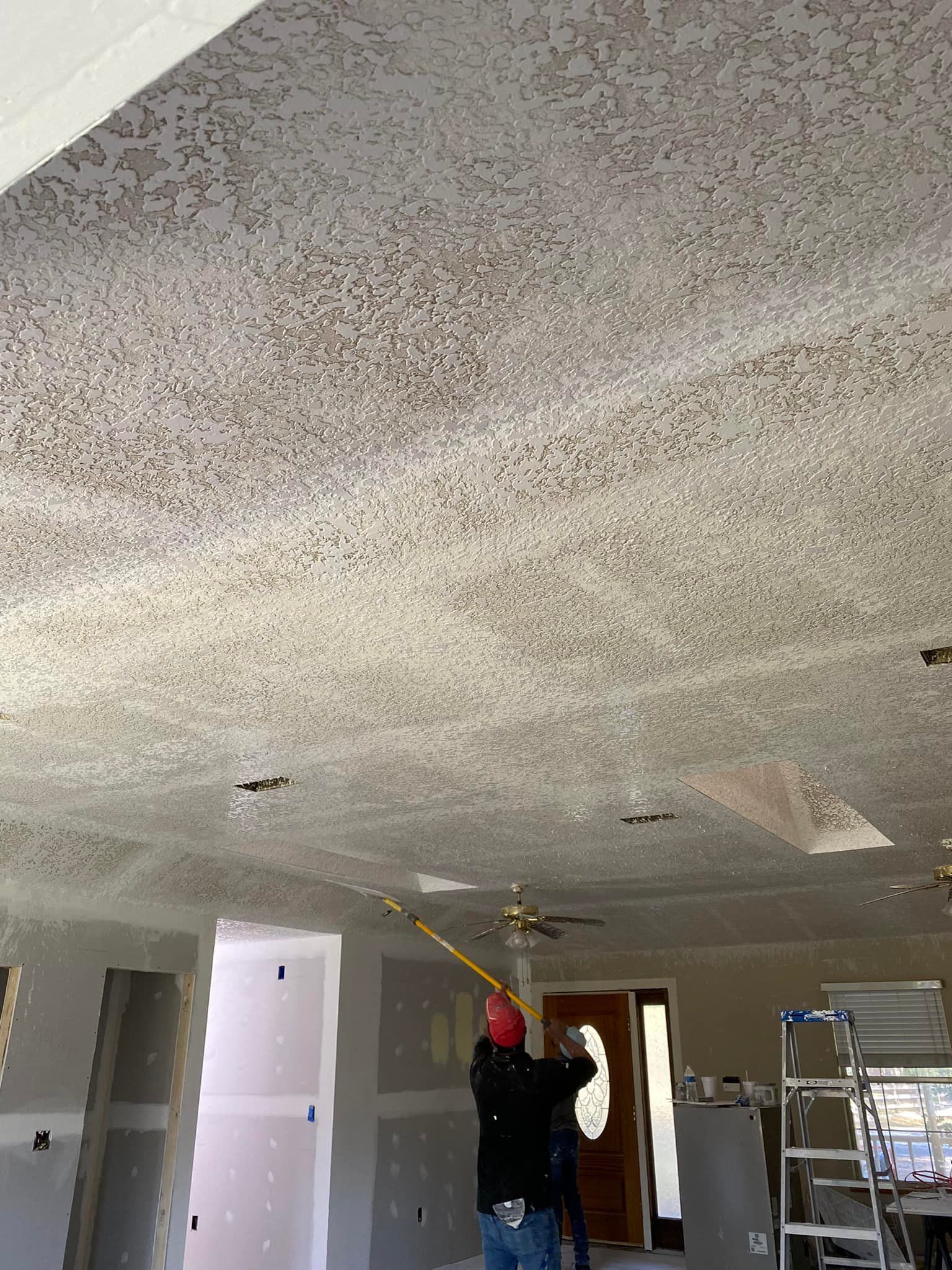 A man is measuring the ceiling of a room with a tape measure.