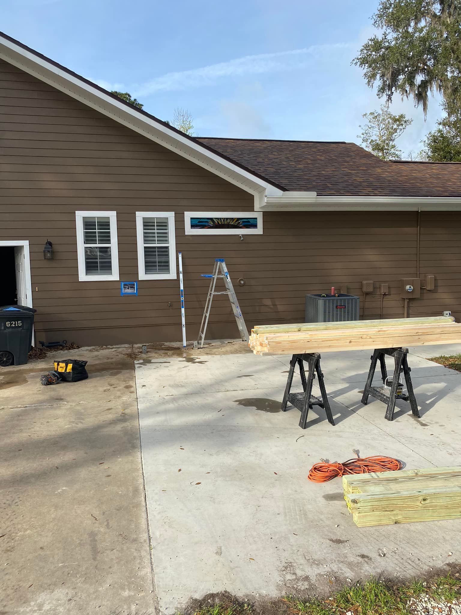 A wooden plank is sitting on a workbench in front of a house.