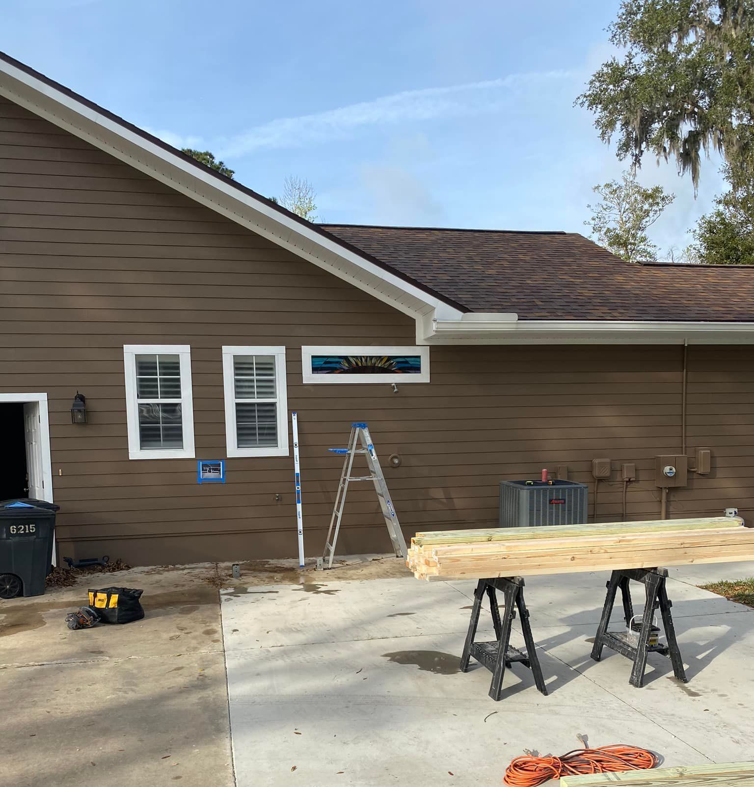 Two men are working on a wooden structure in front of a house.