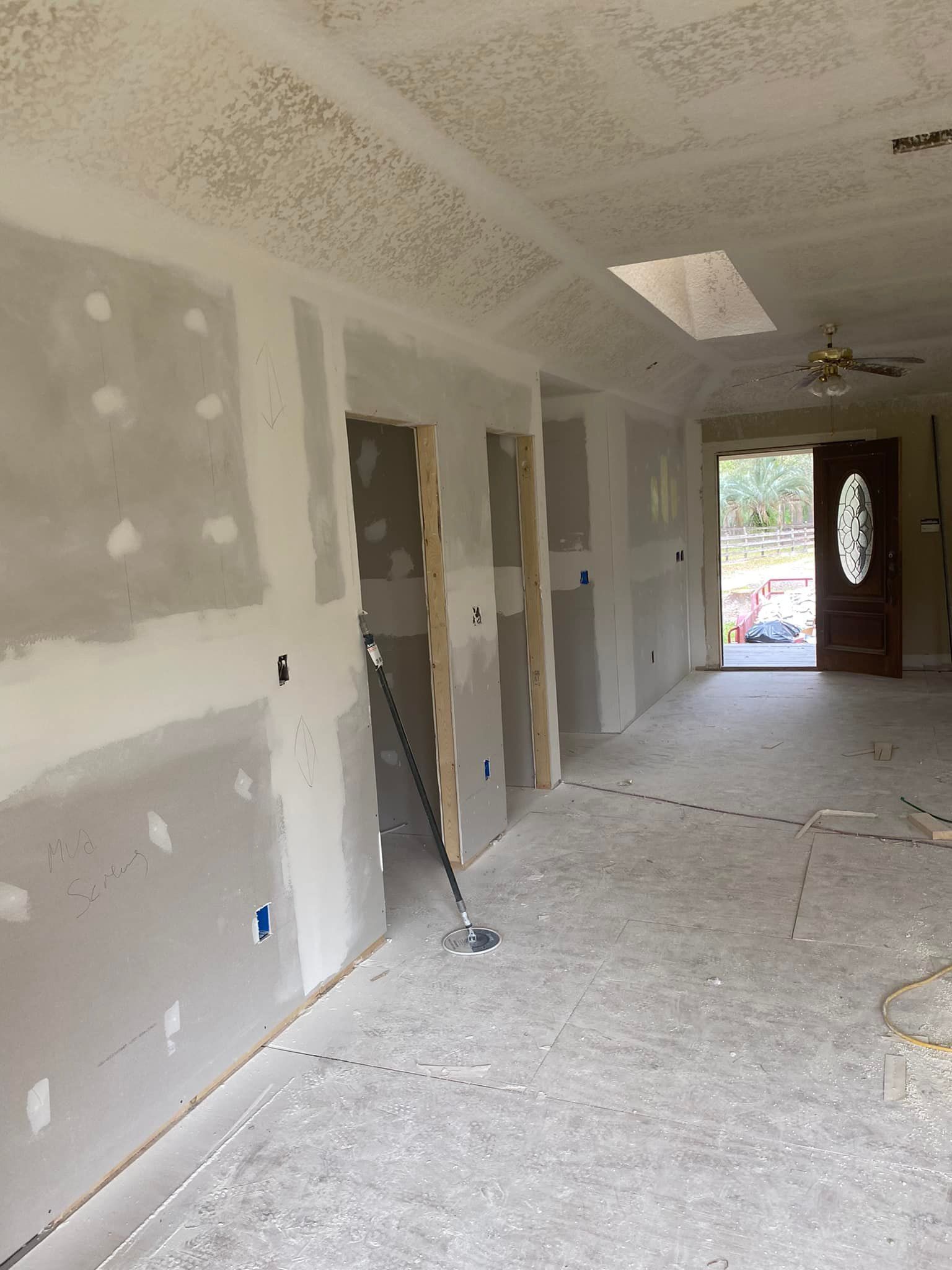 An empty room with a ceiling fan and a door.