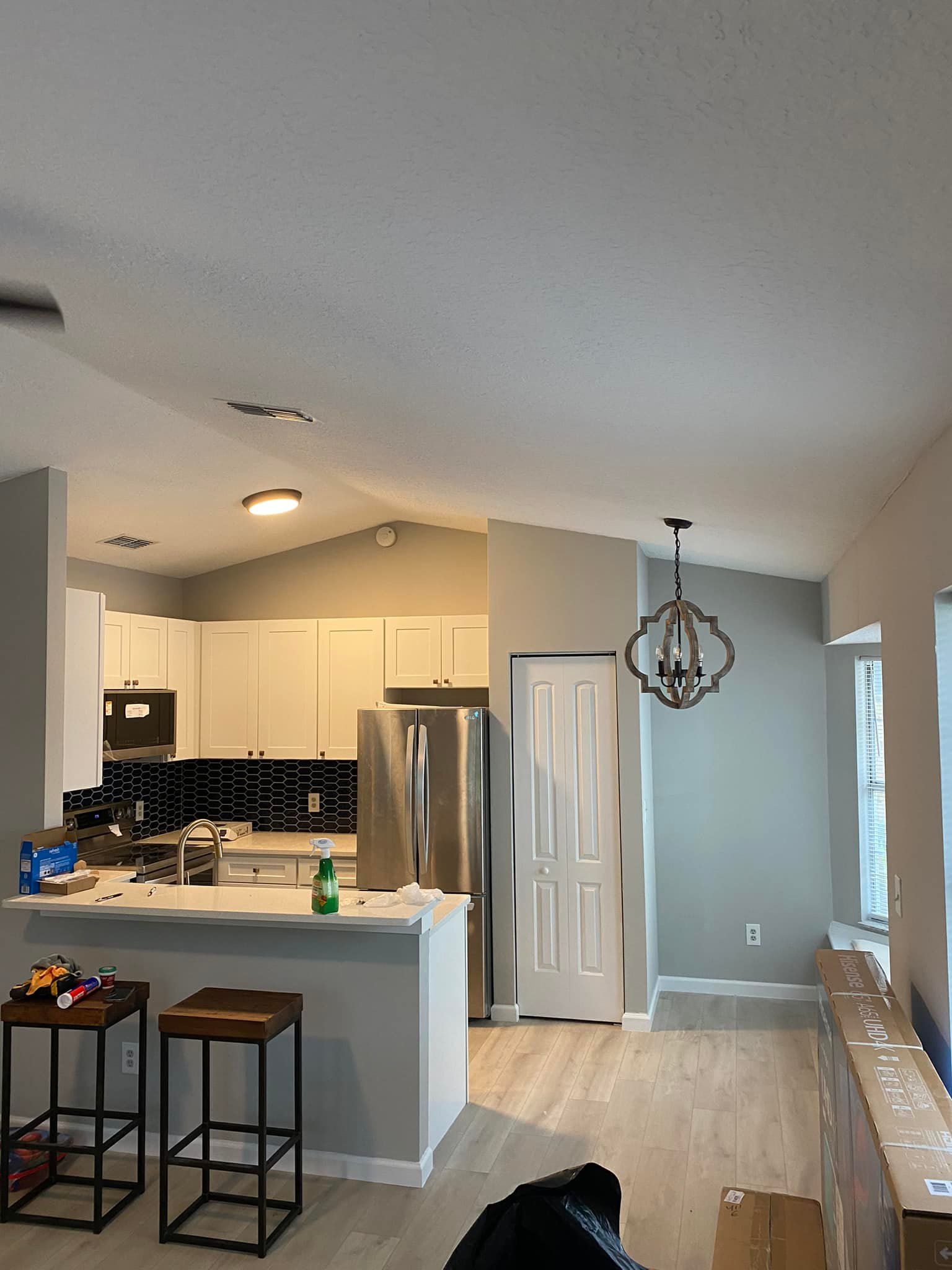 A kitchen with white cabinets , stainless steel appliances , and a chandelier hanging from the ceiling.