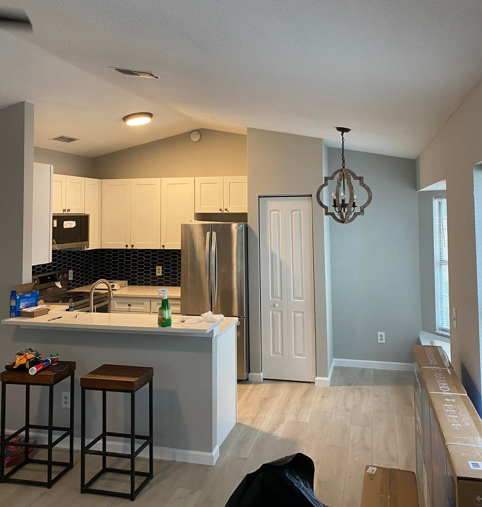 A kitchen with stools and a stainless steel refrigerator
