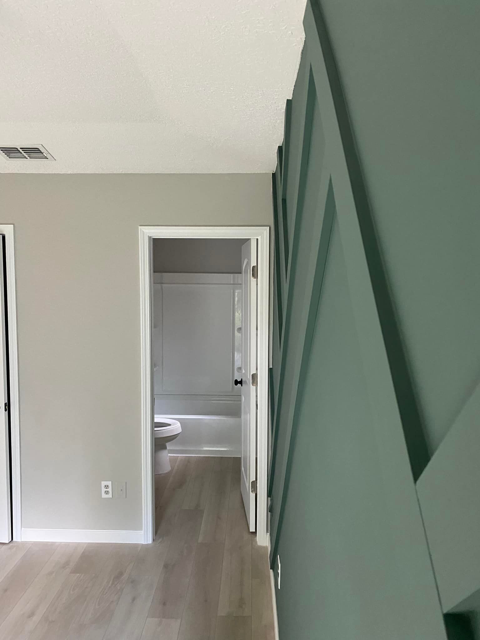 A hallway leading to a bathroom and a toilet in a house.