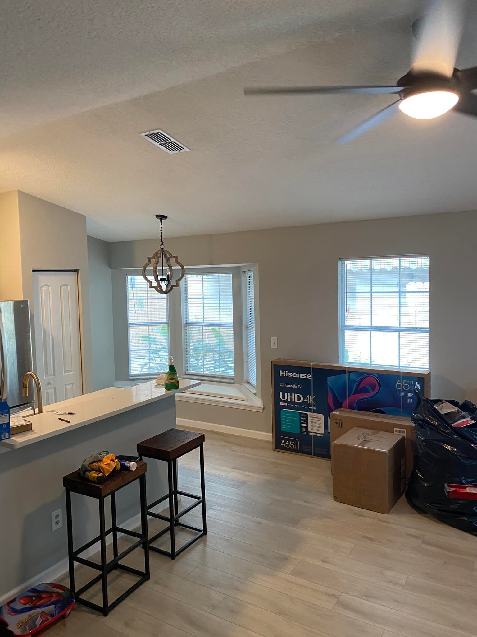 A living room with a ceiling fan and stools.