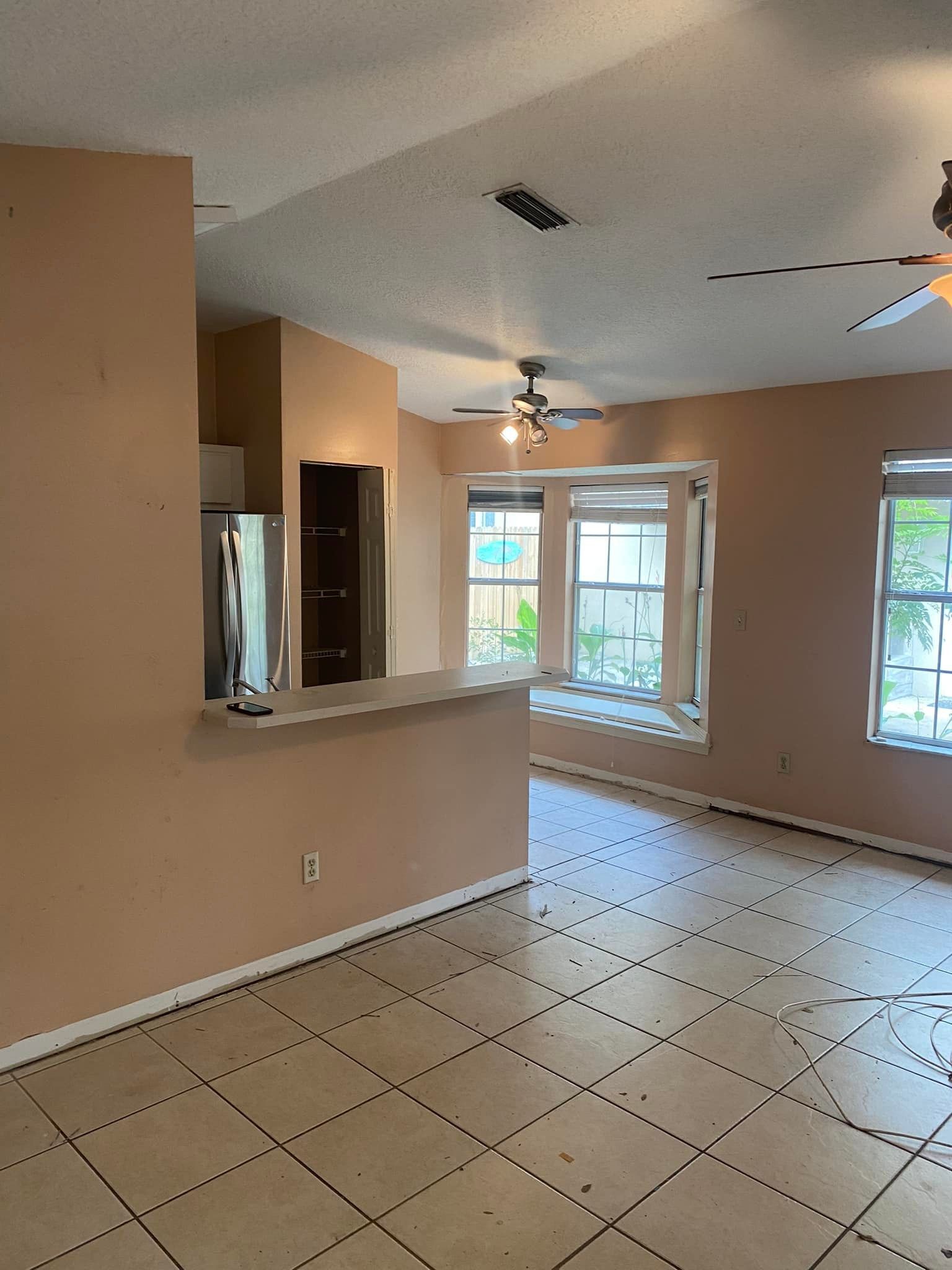 An empty living room with tile floors and a ceiling fan.