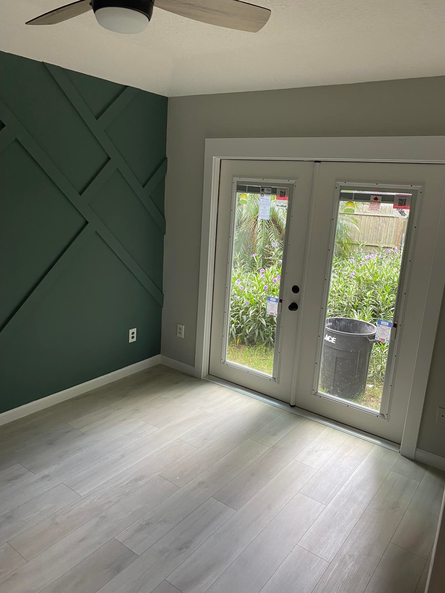 An empty room with a ceiling fan and sliding glass doors.
