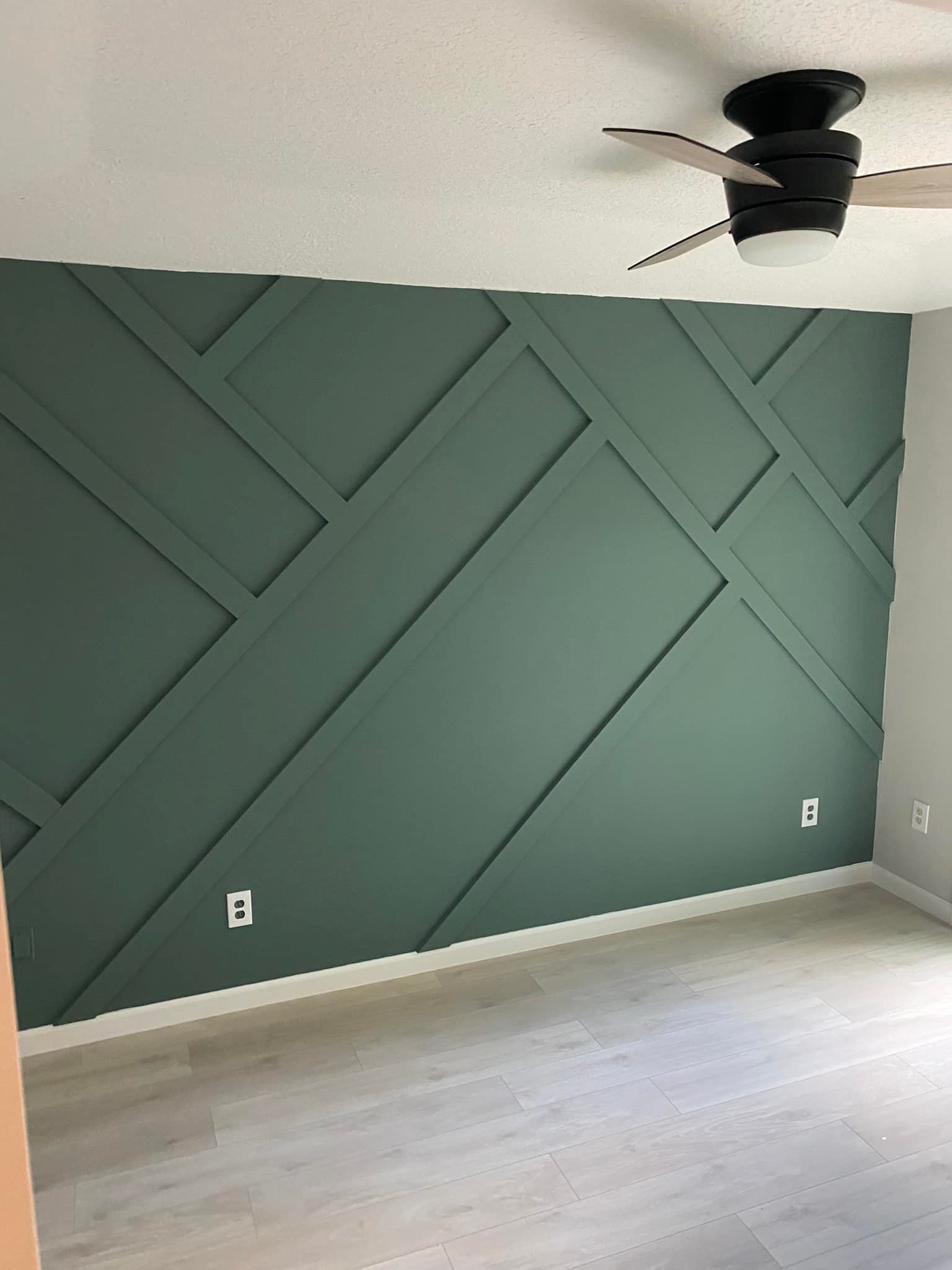 A room with a green wall and a ceiling fan.