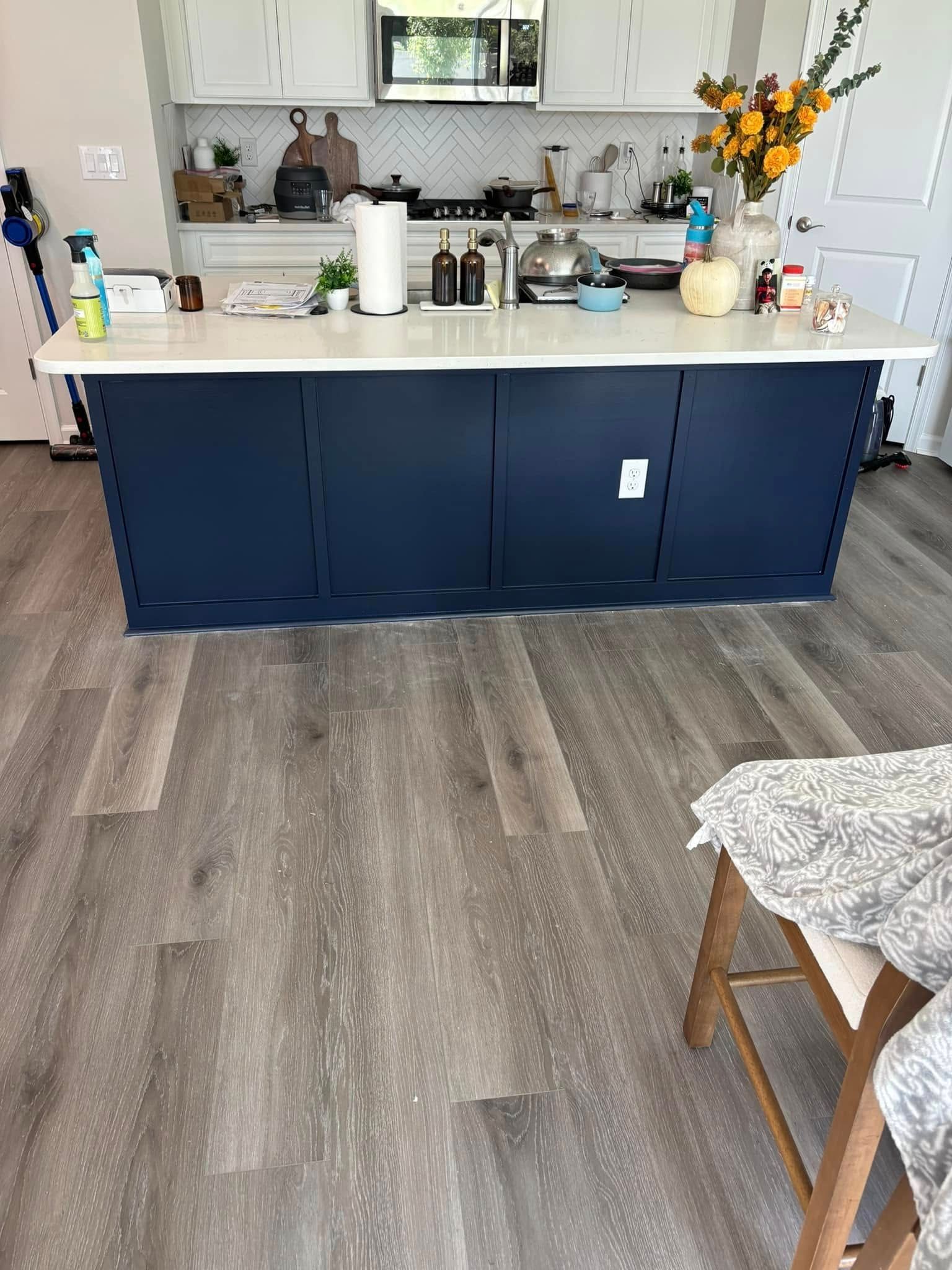 A kitchen with a blue island and a wooden floor.