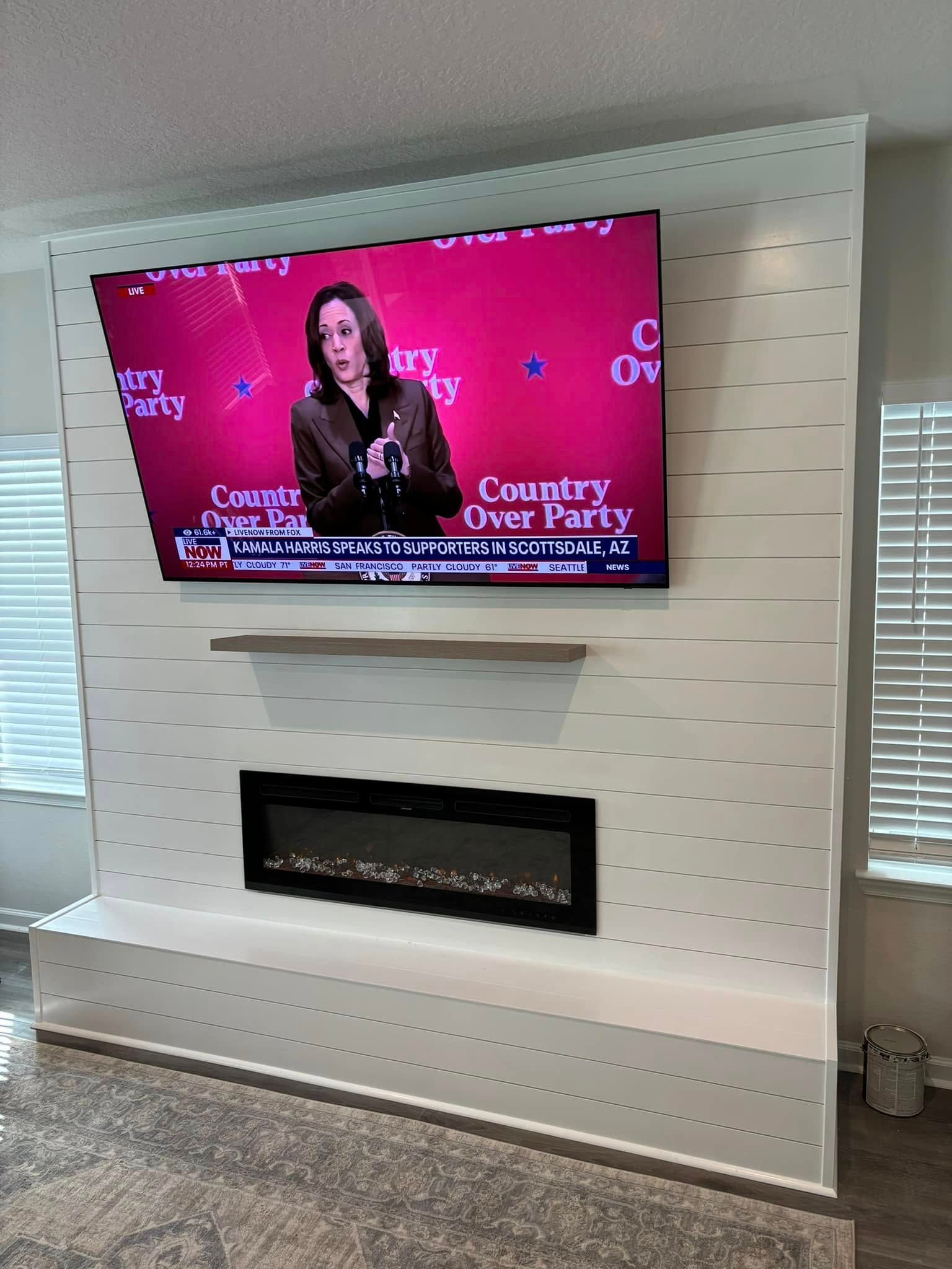 A flat screen tv is hanging on a wall above a fireplace.