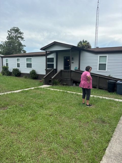 A woman in a pink shirt is standing in front of a mobile home.
