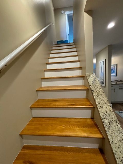 A set of wooden stairs with white steps and a white railing