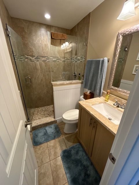 A bathroom with a toilet a sink and a walk in shower