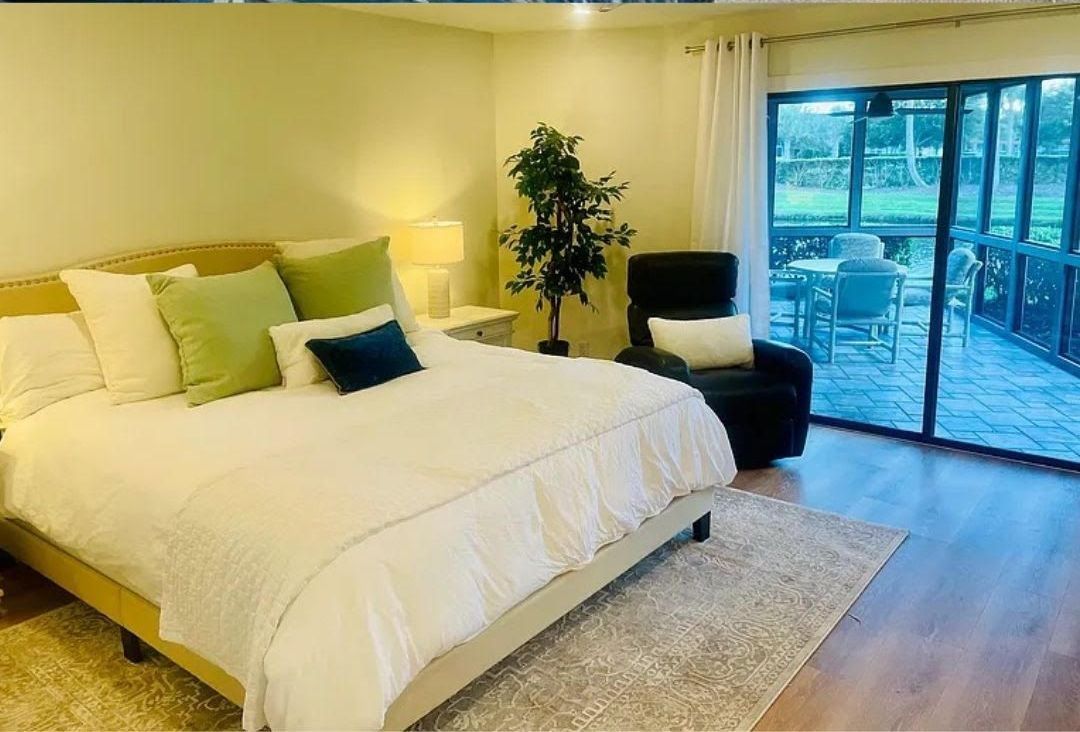 A bedroom with a king size bed , chair and sliding glass doors.