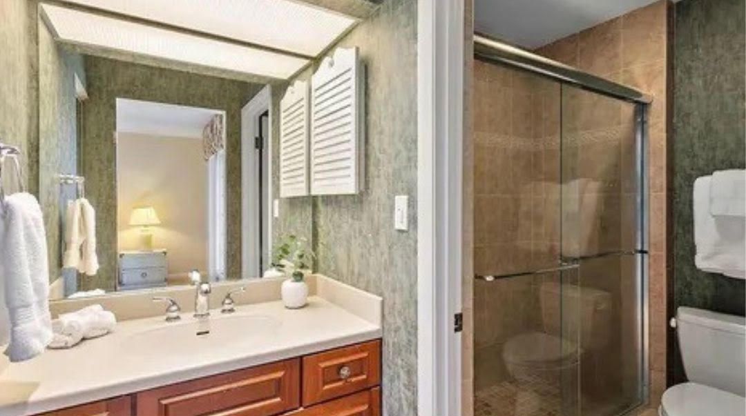 A bathroom with a sink , toilet , shower and mirror.
