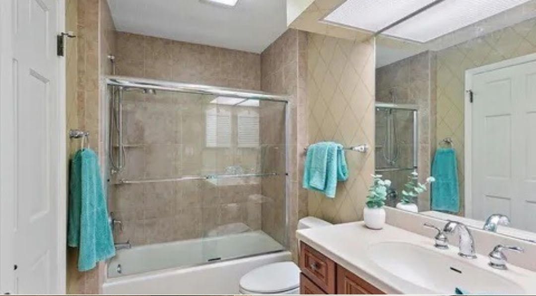 A bathroom with a tub , toilet , sink and mirror.