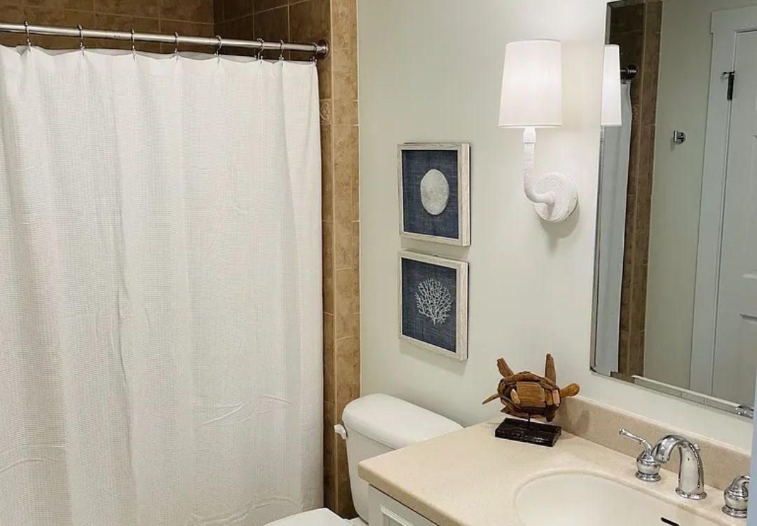 A bathroom with a sink , toilet , shower curtain and mirror.