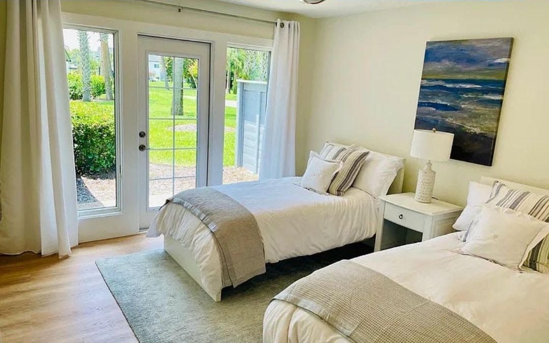 A bedroom with two twin beds and a painting on the wall.