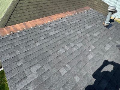 A close up of a roof with shingles and a chimney.
