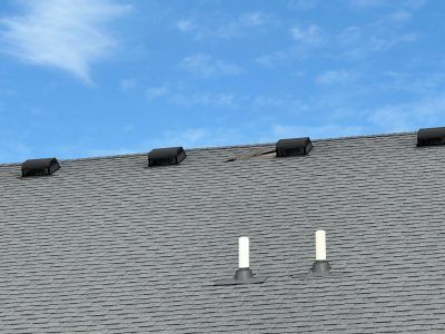 A roof with two chimneys on it and a blue sky in the background.