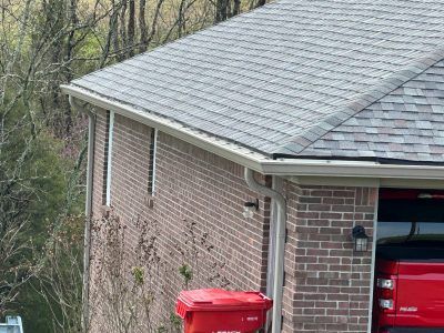 A red truck is parked in front of a brick house.