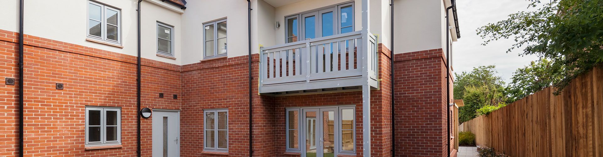 A large brick building with a balcony and a wooden fence in front of it.