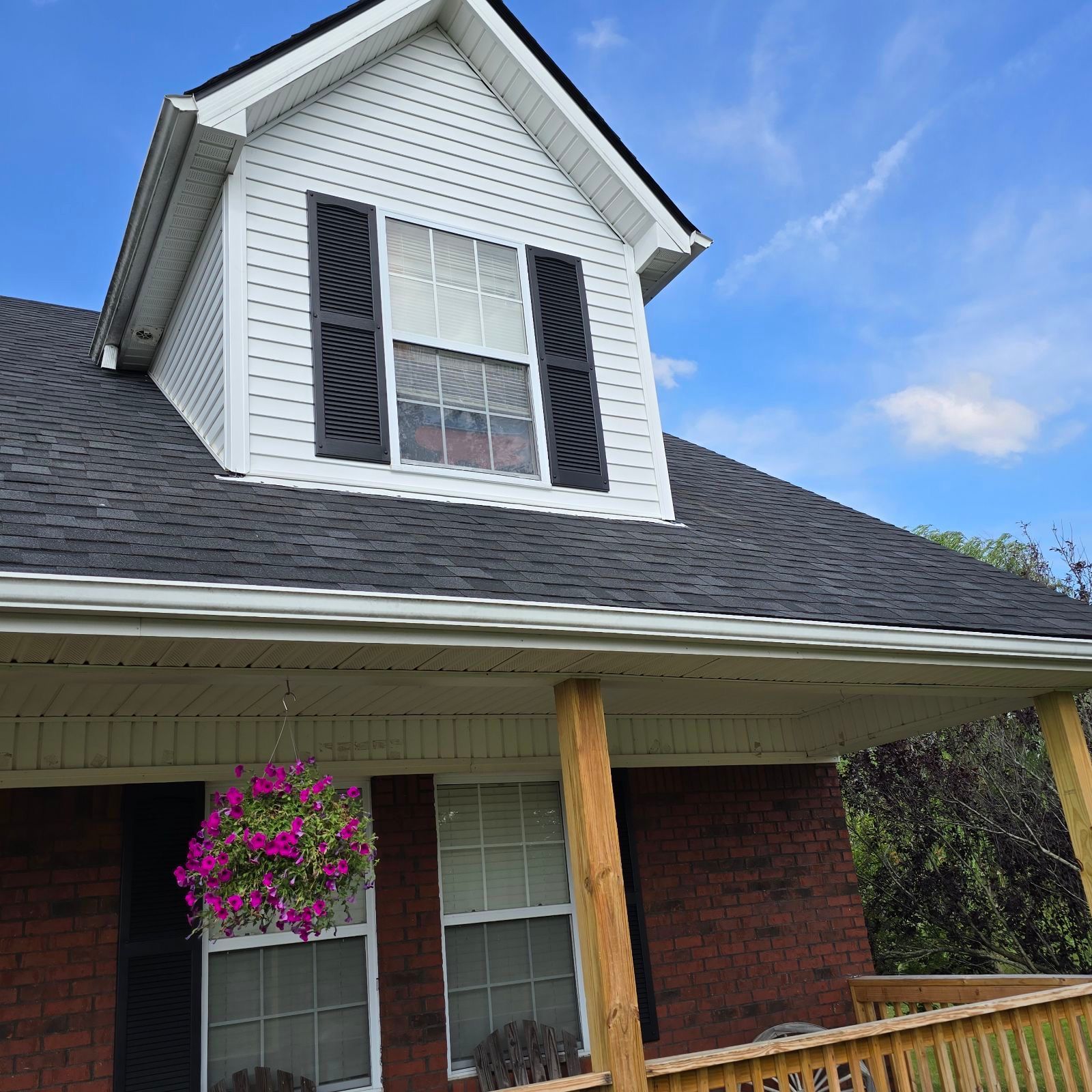 A brick house with a white roof and black shutters