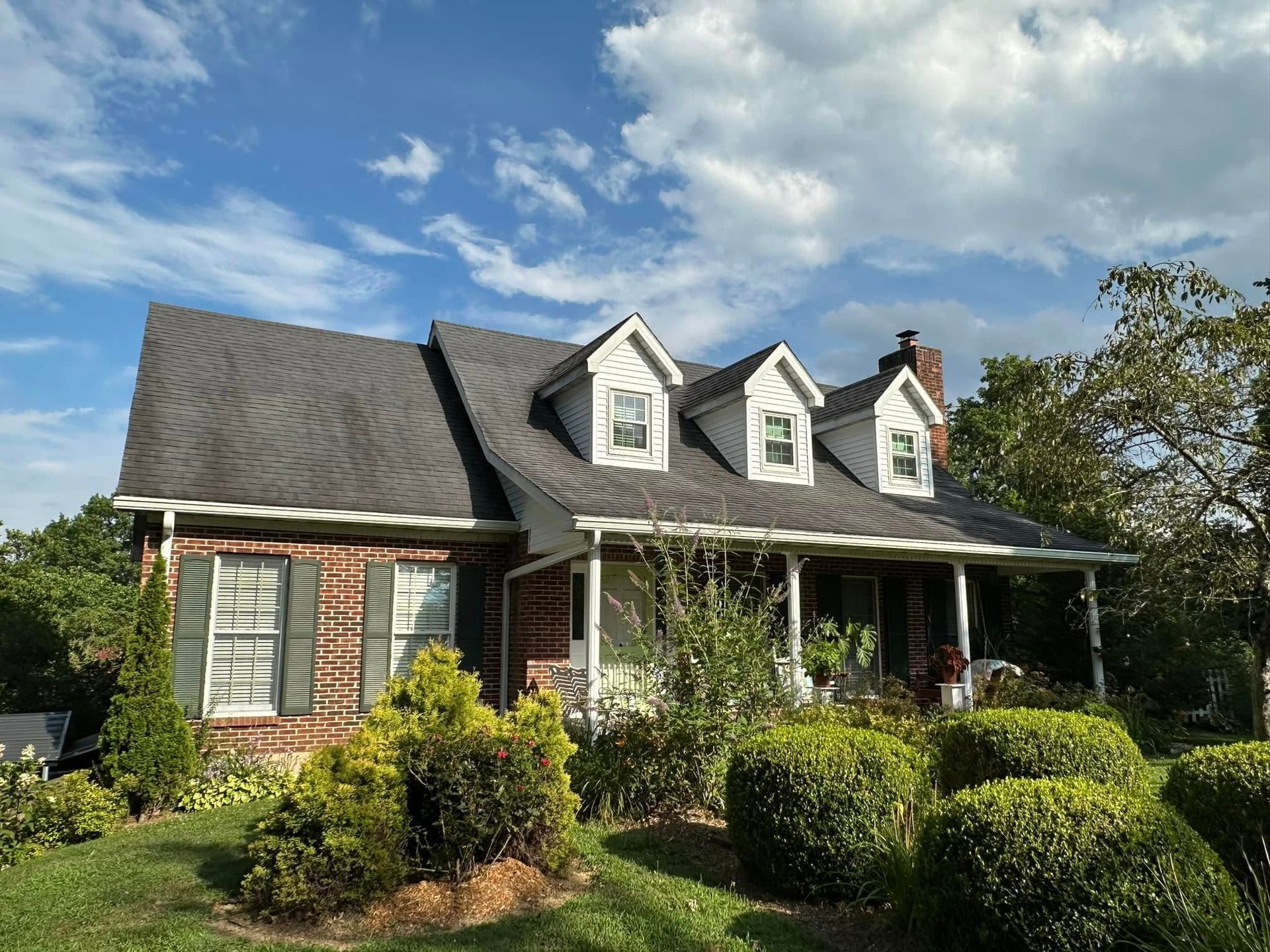 A brick house with a porch and a gray roof