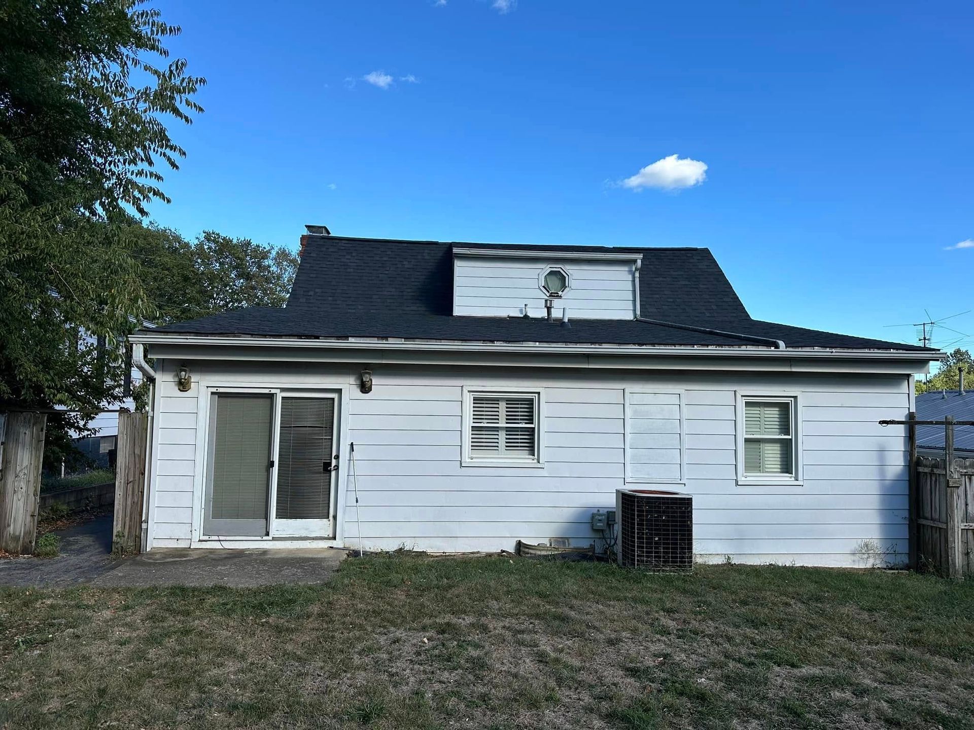 The back of a white house with a black roof and a sliding glass door.